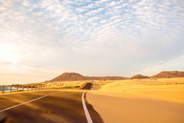 Fototapeta na wymiar Sandstorm on the desert road on Corralejo dunes on Fuerteventura island in Spain