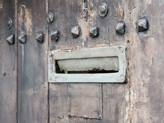 Ancient iron letterbox slot on brown wooden background, vintage style, intentionally blurred.