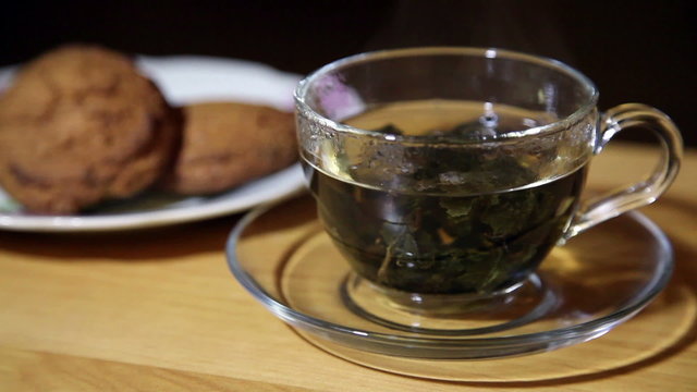 glass cup with tea and biscuits on a plate closeup