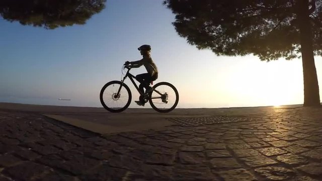 Girl cycling at sunset by the sea