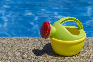 Plastic watering can near swimming pool