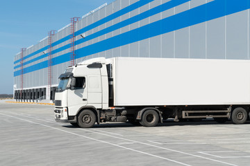 Loading dock of large warehouse with white truck under loading