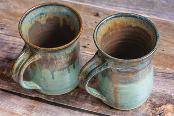 Two Rustic Clay Mugs on a Old Barn Board Floor Close Up