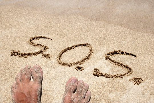 Conceptual S.O.S. handwritten in sand for natural, symbol, tourism or conceptual designs background