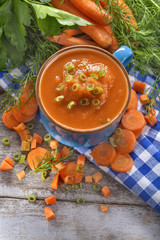 cream soup of carrots in a blue bowl on a rustic wooden table