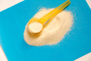 Powdered Milk, Baby Formula with spoon infant formula in can and bottle for feeding baby on blue wooden table. dairy food for baby  spilling out of a measuring scoop.