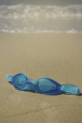 Fototapeta na wymiar Blue goggles on the beach sand