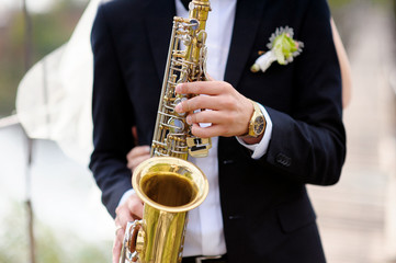Fototapeta premium Hands of groom play on saxophone