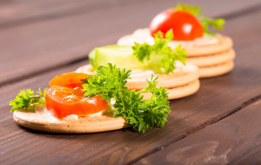 Vegetables on crackers on a wooden table