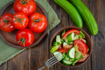 spring vegetables. tomatoes, cucumbers and lettuce on a wooden b