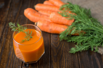 Carrot juice and fresh carrot on a wooden background