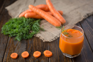 Obraz na płótnie Canvas Carrot juice and fresh carrot on a wooden background