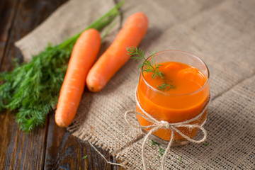 Carrot juice and fresh carrot on a wooden background