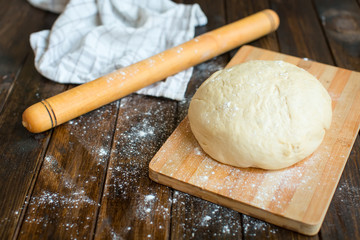 Ball of dough on a rustic wooden background with dusting of flou