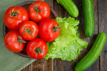 spring vegetables. tomatoes, cucumbers and lettuce on a wooden b