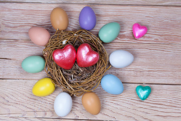 Easter colorful eggs in bird nest on wooden background