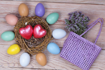 Easter colorful eggs in bird nest on wooden background