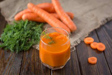 Carrot juice and fresh carrot on a wooden background