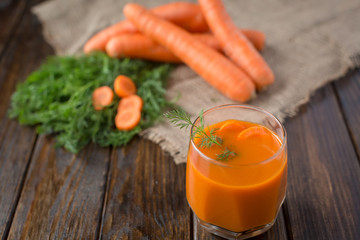 Carrot juice and fresh carrot on a wooden background