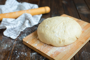 Ball of dough on a rustic wooden background with dusting of flour