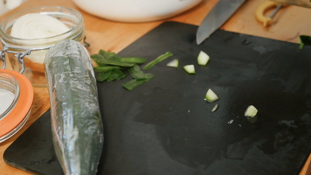 Man preparing at home fresh vegetarian salad from organic ingredients - cutting lettuce and rucola leaves
