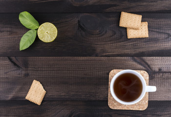 Fototapeta na wymiar a cup of tea with tea cookies and fresh lime on wooden background