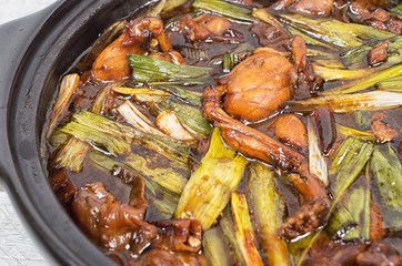 Singaporean Claypot Frog Legs with Green Spring Onions on a wood
