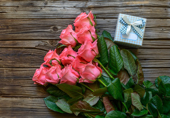 Bundle of roses and gifts on table