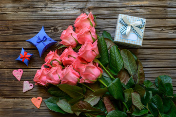 Bundle of roses and gifts on table
