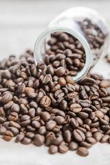 Coffee beans in a glass bottle on wood background