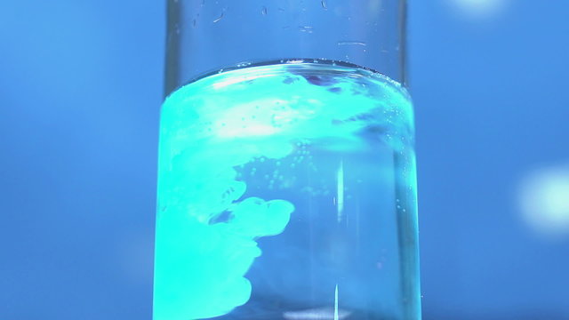 Glowing fluorescent substance mixed with clear water in chemistry bottle at lab