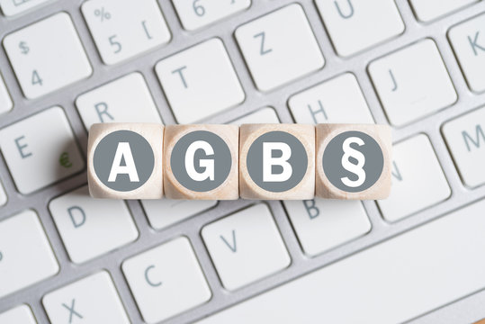 Würfel mit Abkürzung AGB und Paragraph Symbol auf einer Tastatur