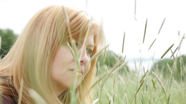 Attractive blond Caucasian girl playing with grass and plants in slow motion 1080p FullHD footage - Slow-mo blond woman in the grass playing 1920X1080 HD video 