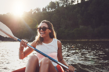Smiling young woman kayaking on a lake - obrazy, fototapety, plakaty