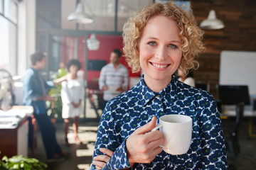 Happy young businesswoman having coffee