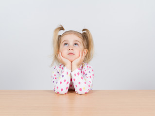 Little girl in casual clothes looking up and thinking