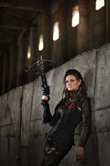 Naklejka premium Raider girl in leather costume with a crossbow at post-apocalyptic world.