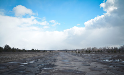 Empty abandoned runway nowadays used as rally racetrack. Hot summer day. Cracks and car tire tracks...