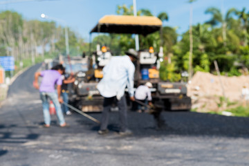 Obraz premium Worker operating asphalt paver machine during road construction