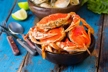 Seafood. Bowl of crabs and soup of slams on wooden blue background. Traditional food on Holy week Easter in Latin America. 