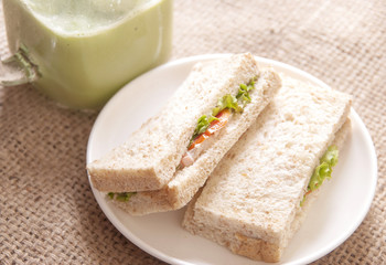 Fototapeta na wymiar Breakfast with sandwich and ice green tea on gunny sack background