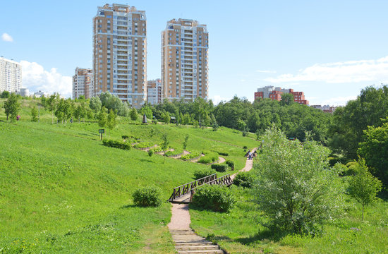 Городской парк на фоне жилых домов летом 