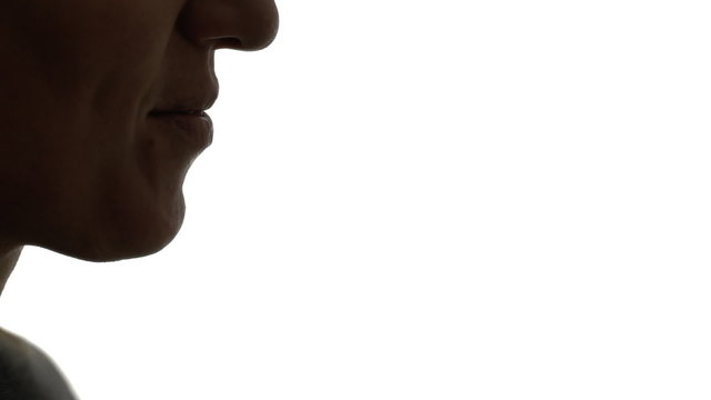 A woman blowing into a whistle. Clear silhouette shot.