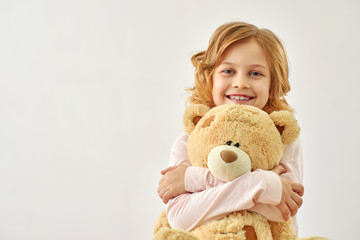 Happy little girl huging bear