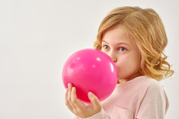 Little girl inflates pink balloon