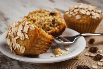 Fresh muffins with oatmeal baked with wholemeal flour on white plate, delicious healthy dessert