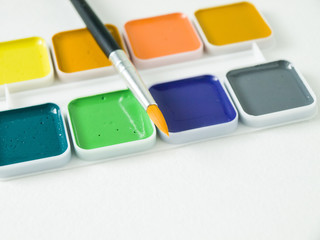 Акварельные яркие краски с кисточкой крупным планом