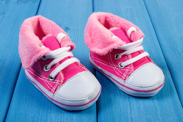 Pair of baby shoes on blue boards, expecting for baby