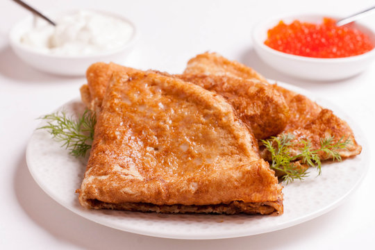 crepes with red caviar and sour cream, isolated on white