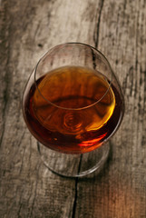 brandy in large round glass on the old wooden background